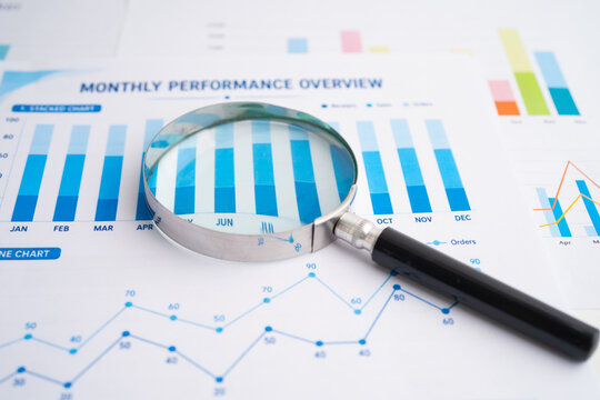 Magnifying glass on spreadsheet and graph paper.