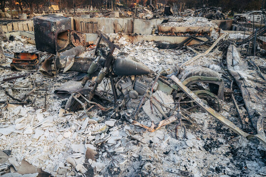 View of a destroyed motorcycle frame, kids' bikes and charred debris in the aftermath of a wildfire in Spokane, Washington, United States.