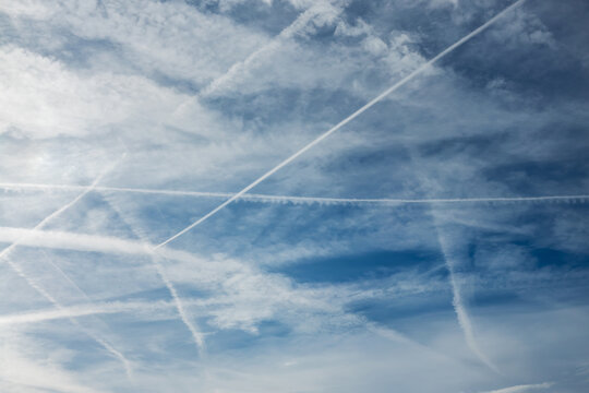 Many contrails (meaning condensation trails) from planes in the sky, airplanes chemtrails conspiration theory, aerial travel and traffic