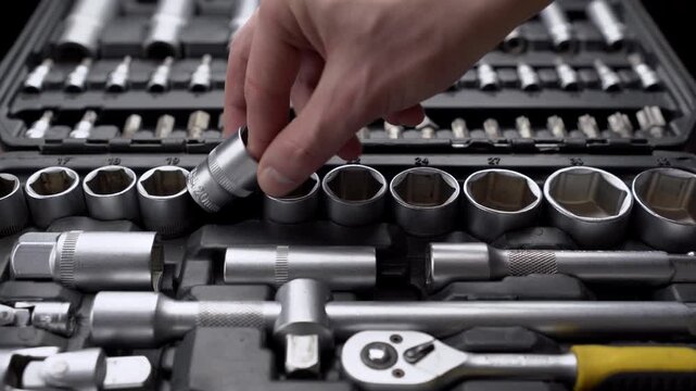 Male hand choosing and pointing at socket head in organized toolbox case close-up, auto mechanic repair concept