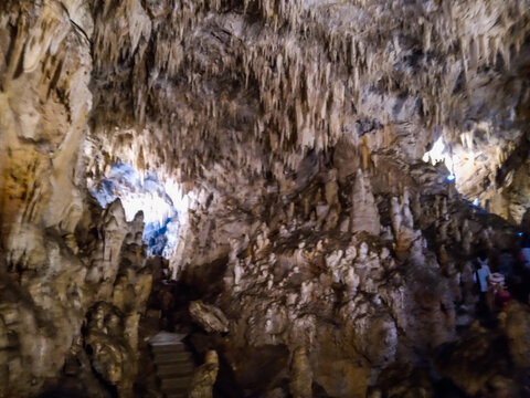 Stalactites and stalagmites create intricate geological formations inside this deep limestone cavern captured with natural lighting and sharp focus to highlight rugged textures and earthy tones.