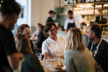 Obraz premium A lively gathering at a restaurant where a group of people share laughter and rich conversations, showcasing the joy of social interactions and the warmth of friendship in dining.