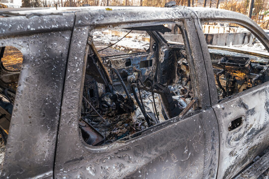 View of a car completely destroyed by the 2026 wildfires, showing charred metal and a gutted interior in Spokane, Washington, United States.