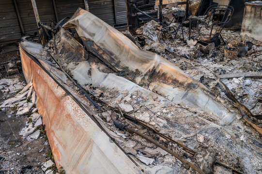 View of fire-damaged debris and charred remains of a structure following a wildfire in Spokane, Washington, United States.