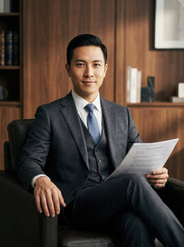 Asian male lawyer holding legal contract in modern law office