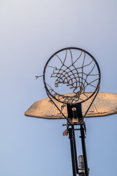 View of a worn basketball hoop with a tattered net set against a clear blue sky in Spokane, Washington, United States.