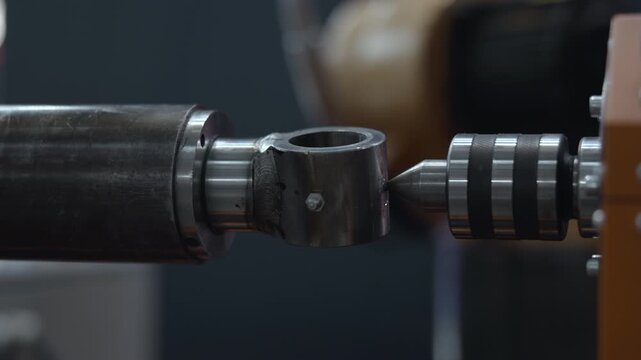 Precision metal coupling and shaft aligned with pointed machine tool inside dim industrial workshop, showing subtle positional shift across ordered views, polished steel reflections, worn housing
