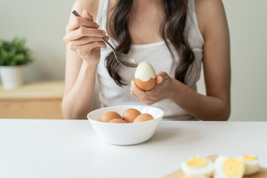 woman holding boil egg and pilling off eggshell