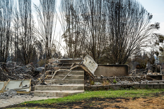 View of the charred remains of a residential property with concrete steps and scorched trees following the wildfires in Spokane, Washington, United States.