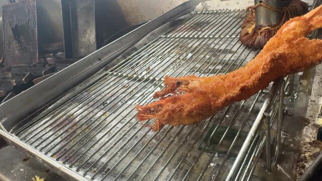 Lifting crispy breaded ebi fry shrimp from hot oil with tongs, Japanese izakaya kitchen, Japan