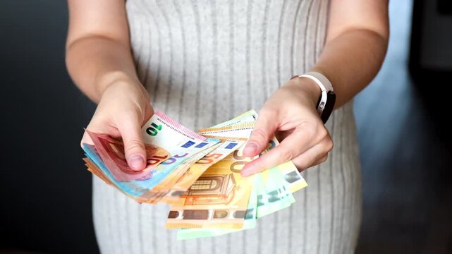 Close-up of female hands counting a fan of euro banknotes. Concept of financial wealth, cash payment and salary.