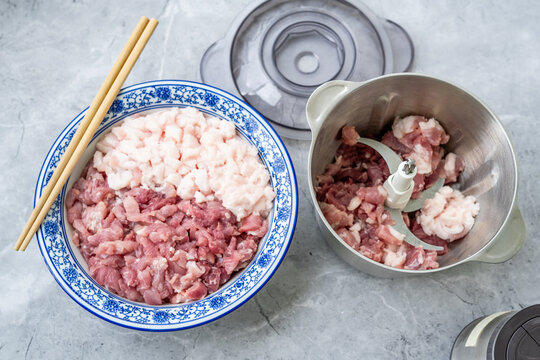 Preparing minced pork: a bowl of fresh pork and a meat grinder.