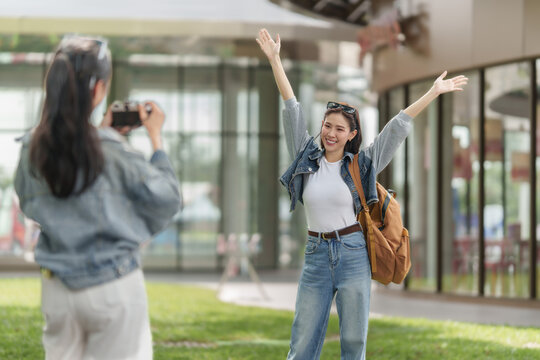 Asian female tourists taking photos outdoors while exploring city for holiday travel