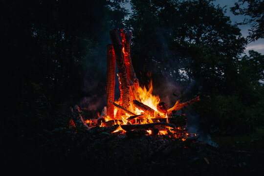 View of a bright bonfire burning with glowing embers and sparks in a dark forest on Vormsi island in Laane County, Estonia.