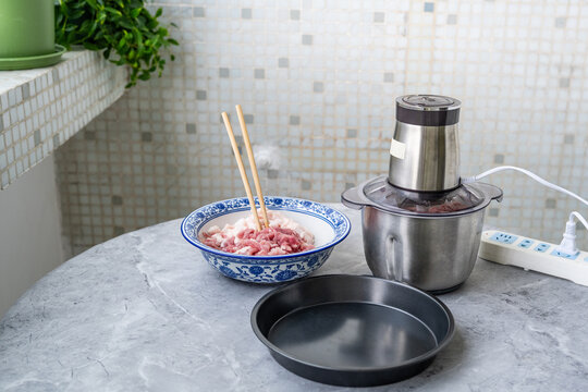 Preparing minced pork: a bowl of fresh pork and a meat grinder.