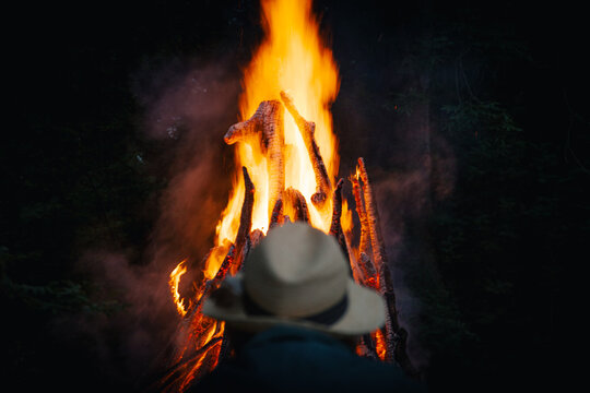 View of a person wearing a hat watching a large bonfire at night on Vormsi, Laane County, Estonia.
