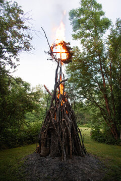 View of a traditional Midsummer bonfire with a burning cross structure in a grassy field on Vormsi island, Laane County, Estonia.
