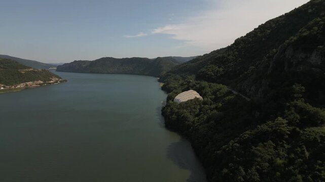 Aerial drone footage of the modern glass protective structure and visitor center at Lepenski Vir archaeological site in Iron Gate National Park, Serbia. 20.07.2026