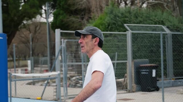 Senior man serving and playing a game of pickleball on a dedicated outdoor court with a partner