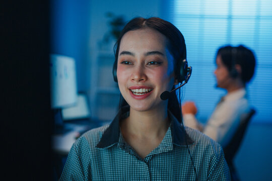 Closeup Gen z Asia young call center team or customer support service executive use computer and microphone headset work technical e commerce in late night office. Telemarketing or sales job concept.