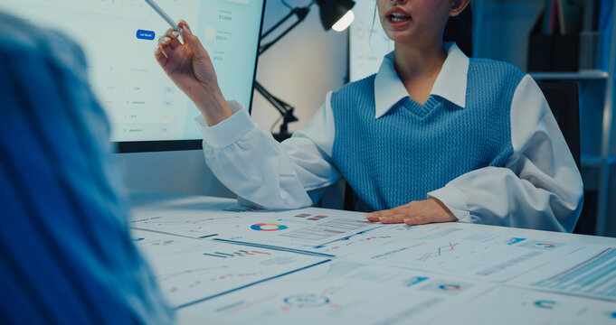 Asia businesspeople presentation sales meeting plan statistics brainstorm and work with paperwork around table in office conference room at night. Business finance partner strategy investment success.
