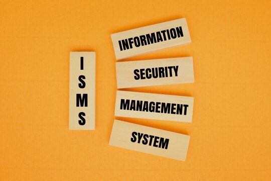 ISMS - "INFORMATION SECURITY MANAGEMENT SYSTEM" text on wooden blocks. Concept for data protection, ISO 27001 compliance, cybersecurity strategy, and corporate risk management on orange background