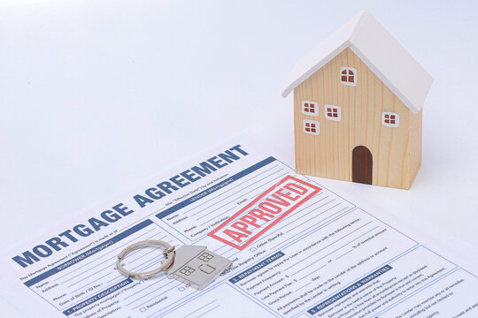 Approved mortgage application document brings happy relief during financial review alongside model home and key on white background