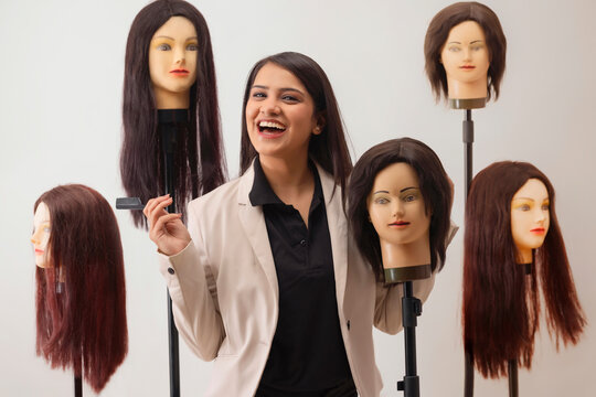A YOUNG HAIRSTYLIST CHEERFULLY POSING WITH DUMMY HAIR