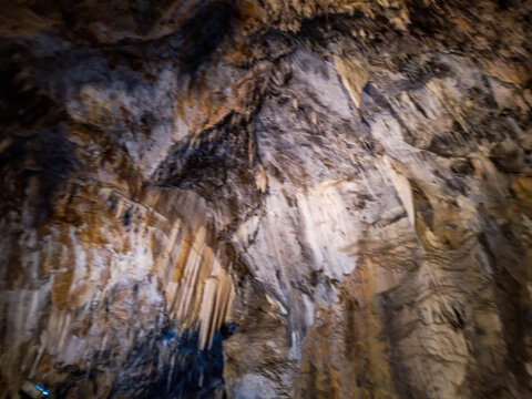 Majestic limestone cavern interior showing intricate stalactite formations with dramatic natural textures and earthy brown tones captured inside this massive subterranean geological wonder 