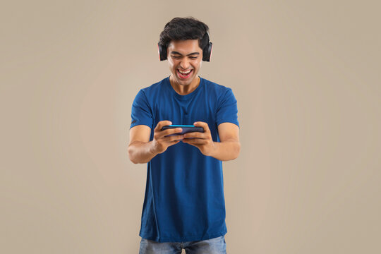 A HAPPY TEENAGE BOY PLAYING VIDEO GAME ON MOBILE