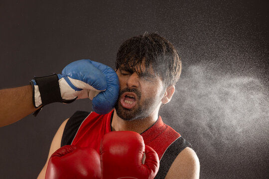 A BOXER BEING PUNCHED ON FACE BY ANOTHER PLAYER WHILE BOXING