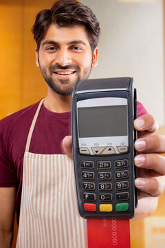 A HAPPY WAITER SHOWING CARD MACHINE IN FRONT OF CAMERA 