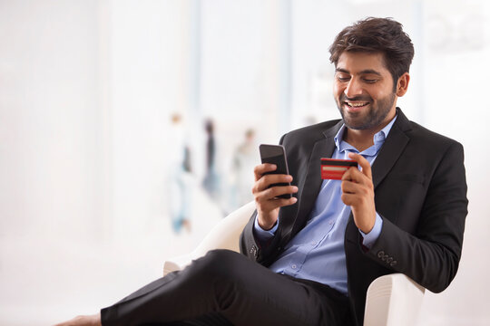 A YOUNG PROFESSIONAL DOING ONLINE TRANSACTION ON MOBILE PHONE