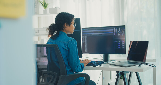 Young professional African American female programmer coding AI software on screens in modern home office. Generative AI, machine learning, digital innovation, future technology, online job concept.