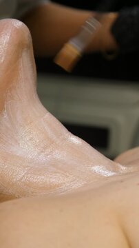 Professional beautician applying cleansing mask on female client's face. Close-up of female face during youth restoration and facial rejuvenation procedure  - Vertical Video