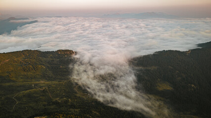 Fototapeta premium Dense sea of clouds flowing through a mountain valley at sunrise