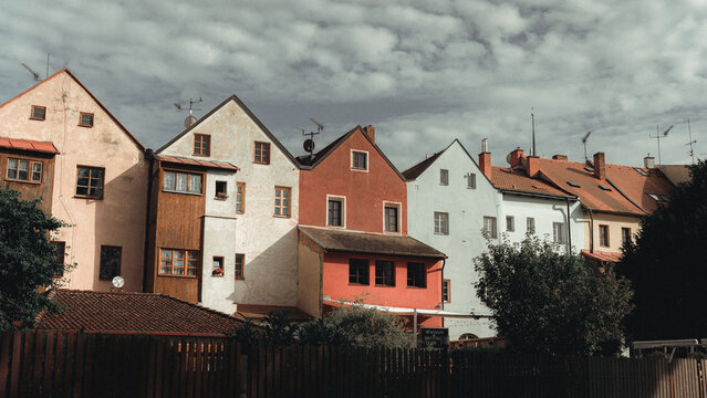 View of a row of colorful historic houses with tiled roofs and varied facades under a cloudy sky in Czech Republic.