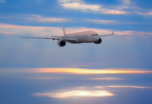 Airplane flying over tropical sea at sunset