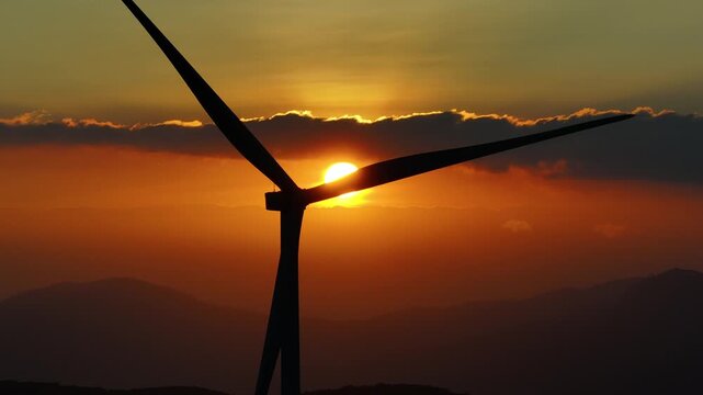 Aerial drone view of Cau Dat tea hills and wind turbines at sunset in Xuan Truong, Da Lat, Lam Dong, Vietnam, showcasing renewable energy and scenic highland landscapes.