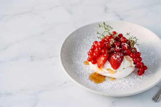 Fresh Berry Pavlova Dessert topped with Strawberries Red Currants and Honey Drizzle