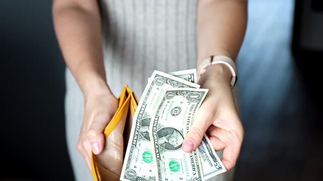 Close-up of female hands showing open empty wallet and last usd banknotes. Inflation, poverty and spending money concept.