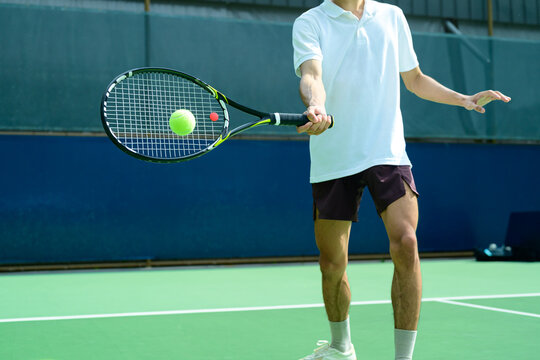 Tennis Player Hitting Ball with Racket on Blue and Green Hard Court Close Up Action Shot