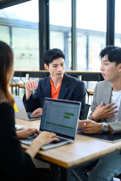 Asian Business Team Meeting with Laptops in Modern Office Space