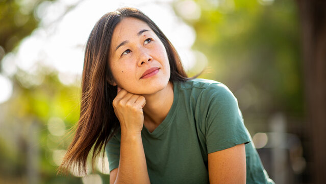Thoughtful Japanese woman looking upward in natural outdoor setting