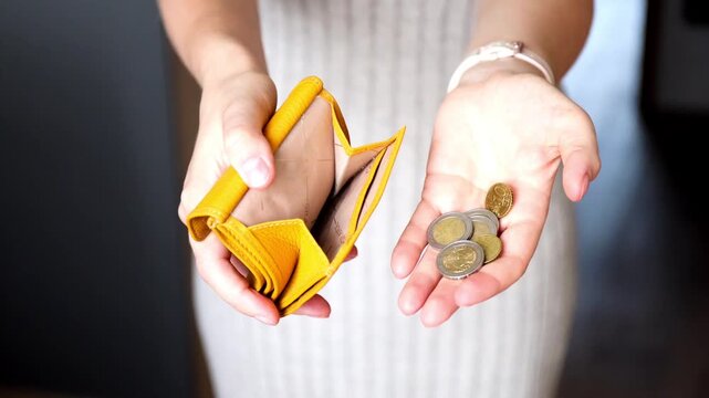 Close-up of female hands holding open leather wallet and small change cash. Inflation, crisis and low income concept.