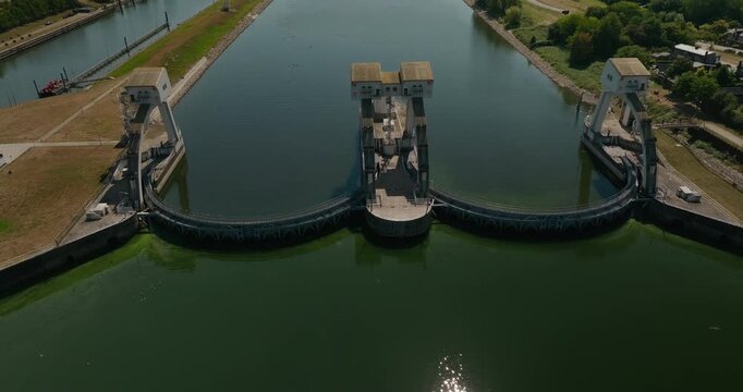 Drone approaches the spectacular steel arch structure of Hagestein Weir Sluice, a major Dutch water control system regulating river water levels and flow on the Lek River.