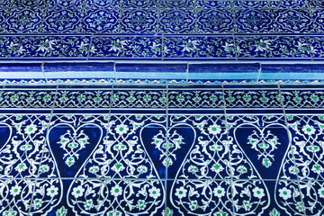 Ornate blue and white ceramic tilework at Pahlavan Mahmud Mausoleum in Khiva, Uzbekistan. Intricate floral arabesque patterns with green accents on glazed majolica tiles, ideal for travel design. © finepoints