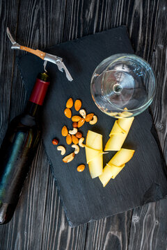 bottle of red wine, appetizers and corkscrew on wooden background