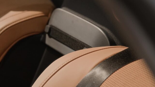 Luxury car seat with perforated beige leather and seatbelt being revealed during slow pan. Footage is ideal for premium automotive commercials and dealership marketing