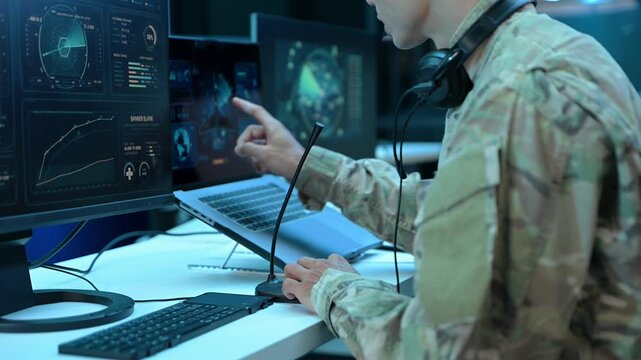 Military operator with headset analyzes radar HUD screens and takes notes in high tech command center, ensuring strategic cyber